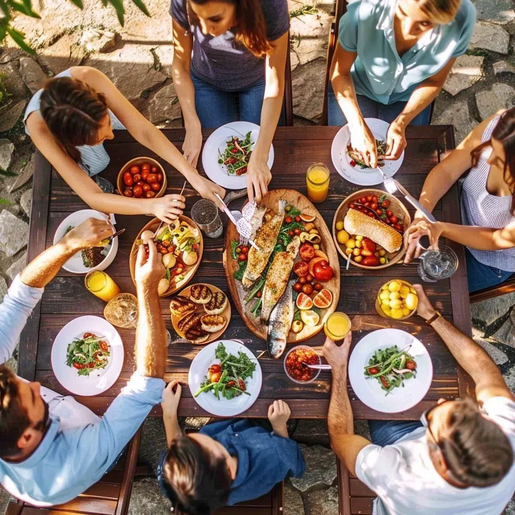 Family gathered around a table enjoying a colorful shared meal outdoors
